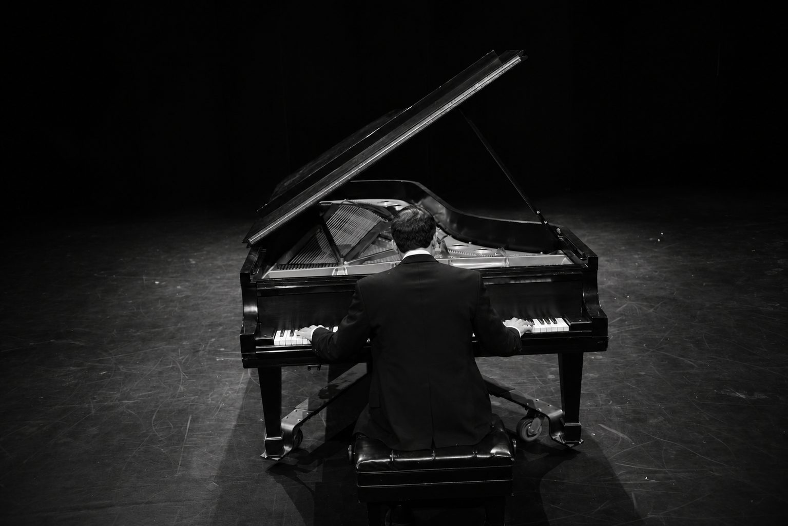 Simone Renzi seen from behind while playing a grand piano