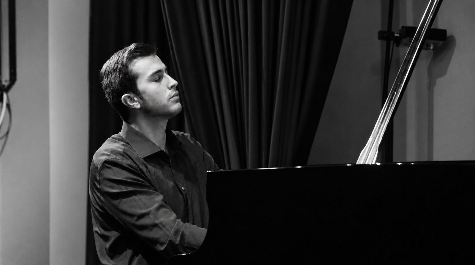 Simone Renzi seduto al pianoforte a coda, ritratto di profilo