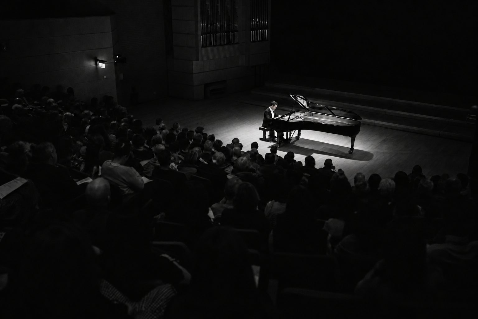 Pubblico in sala e pianoforte illuminato al centro del palco