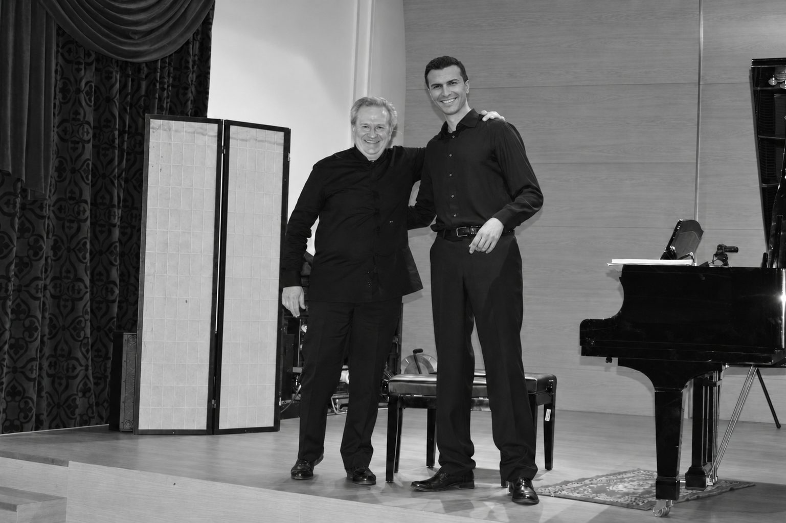 Simone Renzi insieme a un altro partecipante sul palco, accanto al pianoforte